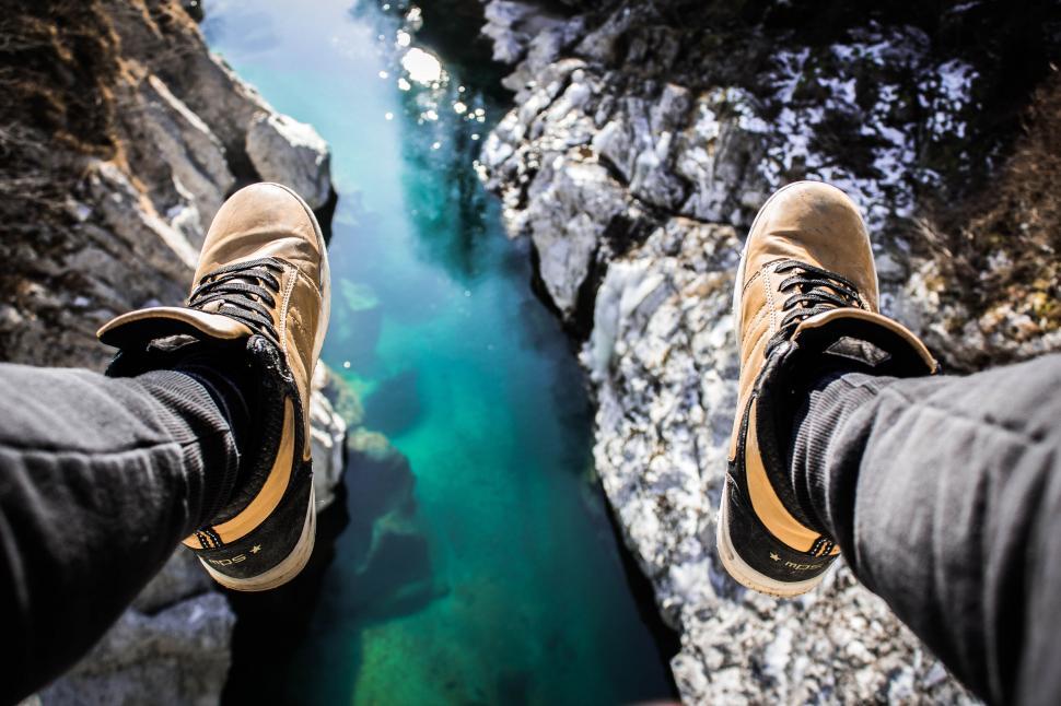 Free Image of Person sitting on ledge above river 