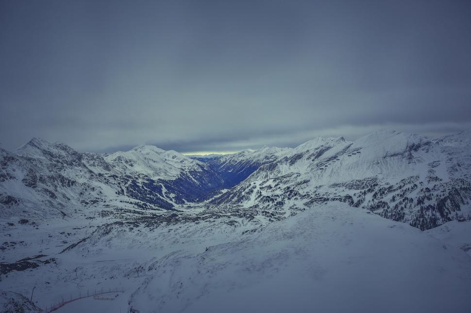 Free Image of Snow-capped mountains under cloudy skies 