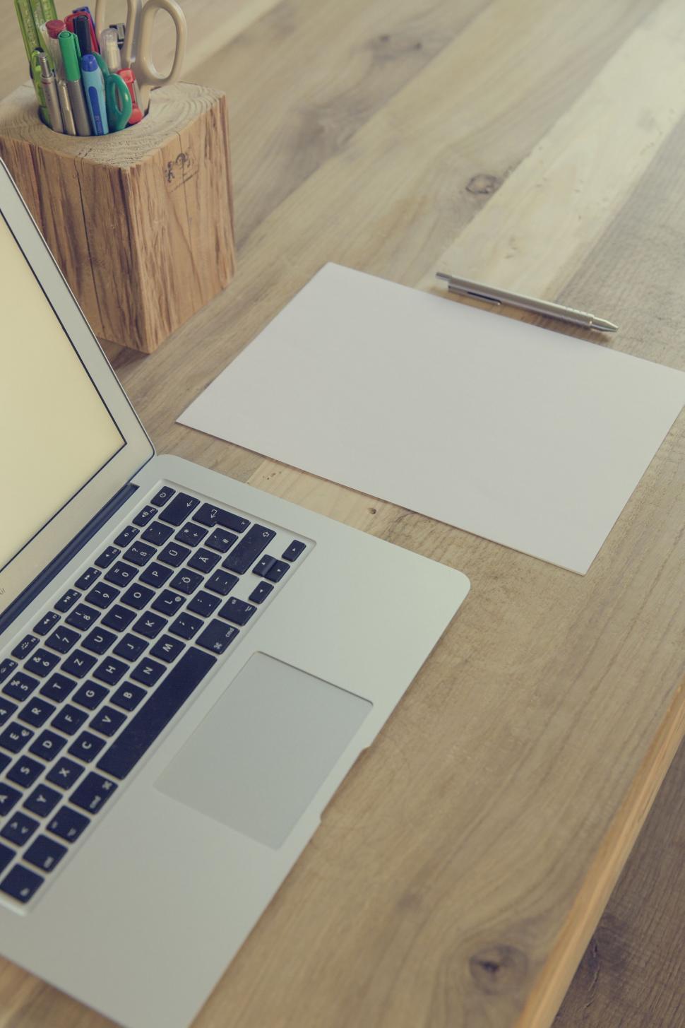 Free Image of Laptop and paper on wooden desk with sunlight 