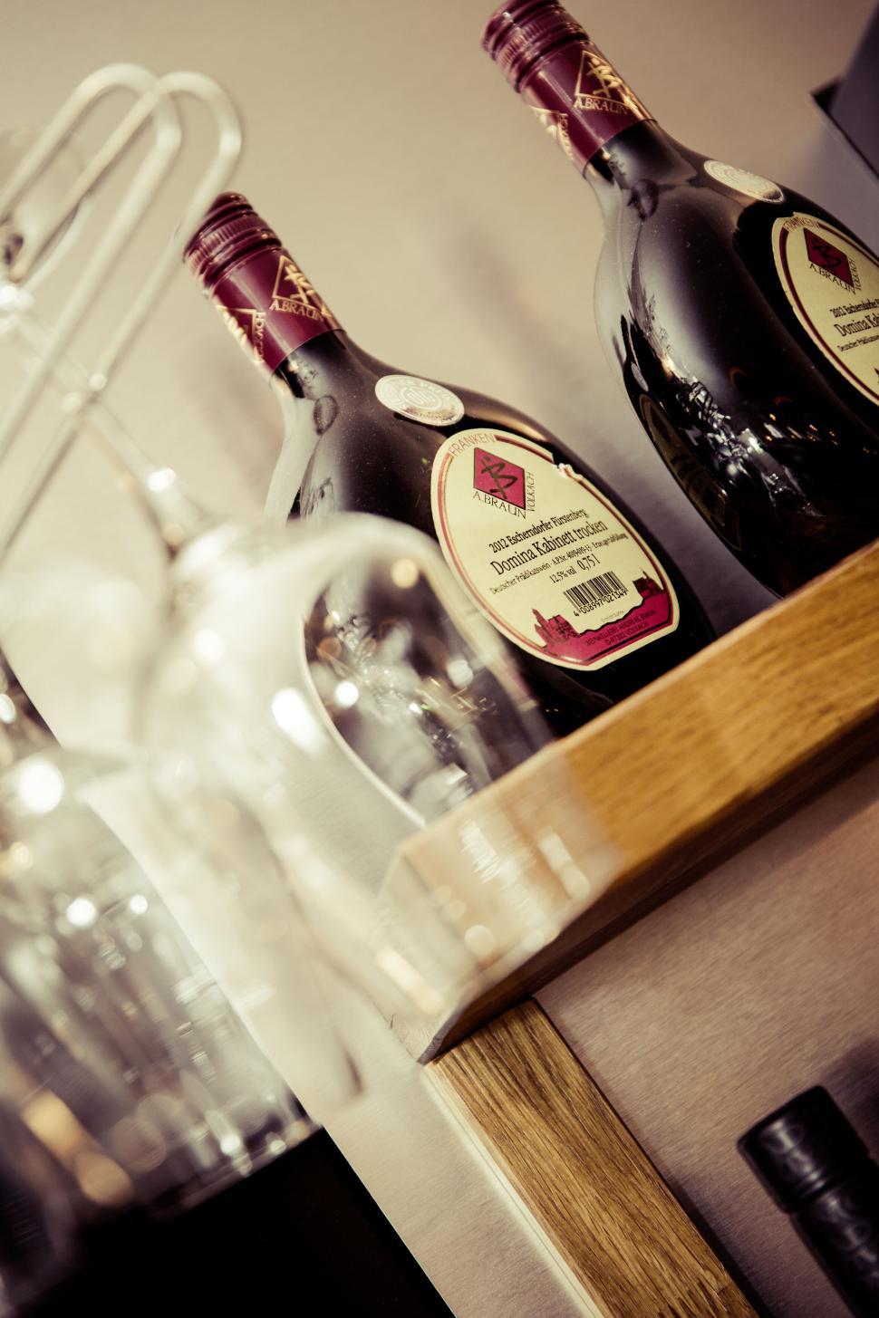 Free Image of Tilted view of wine bottles on wooden shelf 