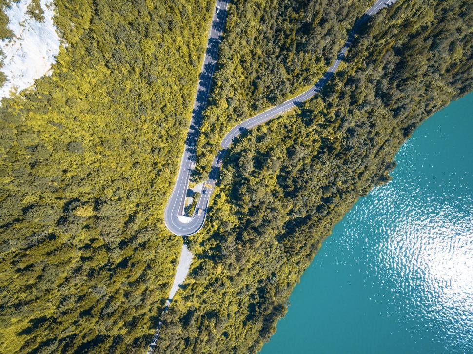 Free Image of Drone photo of winding road near a forested lake 
