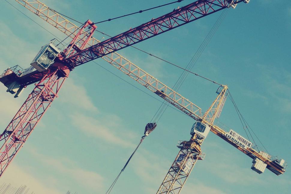 Free Image of Red construction cranes against blue sky 