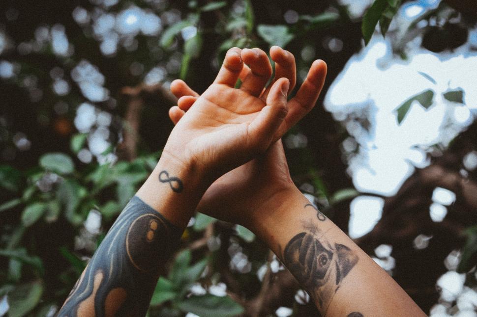 Free Image of Tattooed arms reaching upwards to the sky 