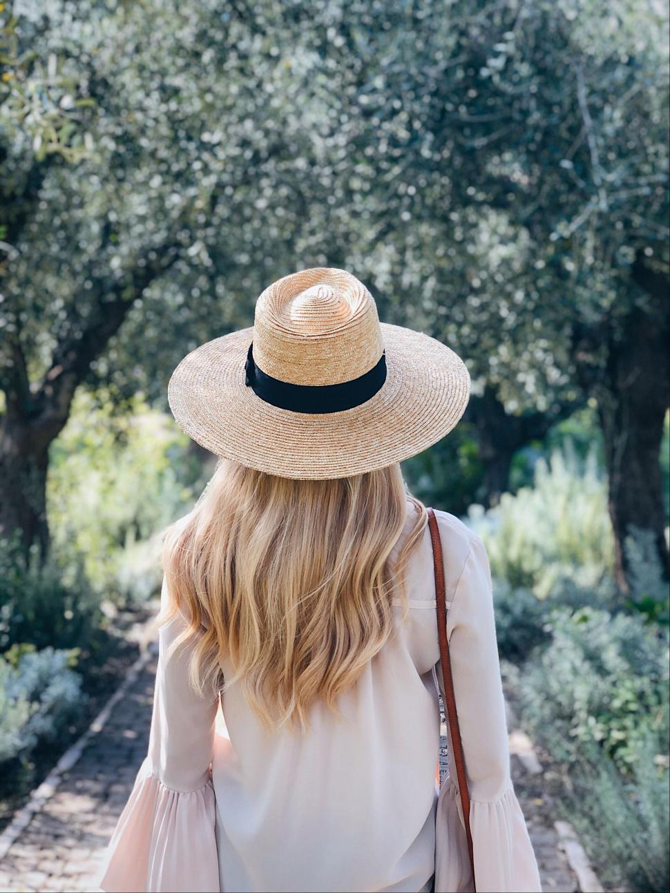Free Image of Woman walking in nature with straw hat 