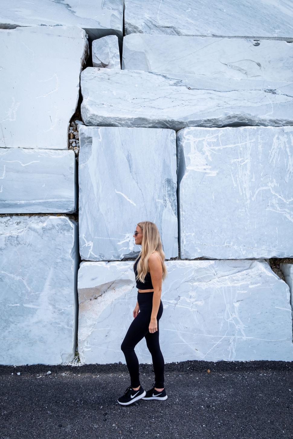 Free Image of Woman standing against a cracked marble wall 