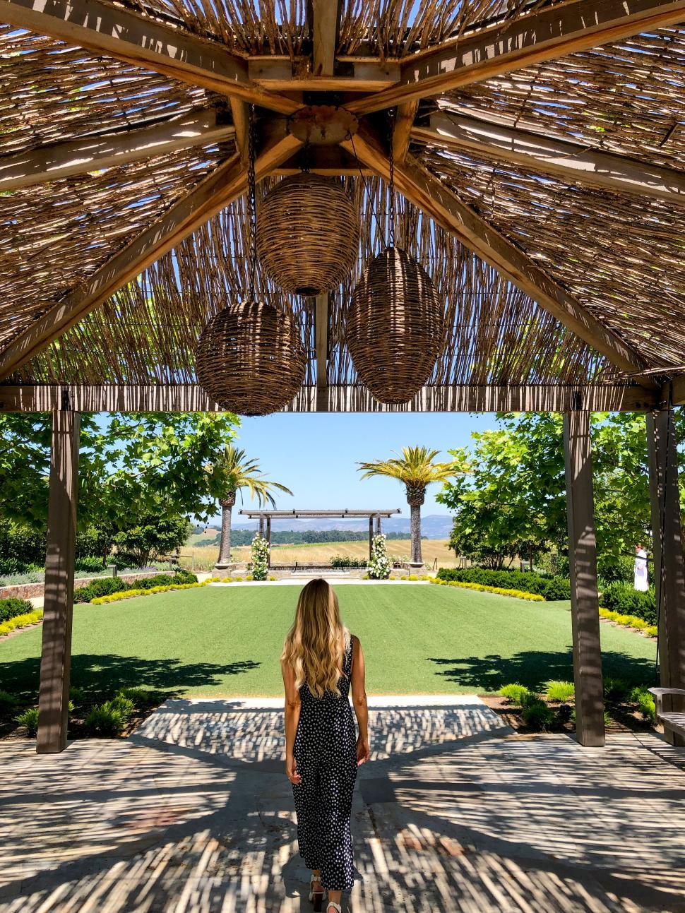 Free Image of Woman standing under straw roof gazebo 