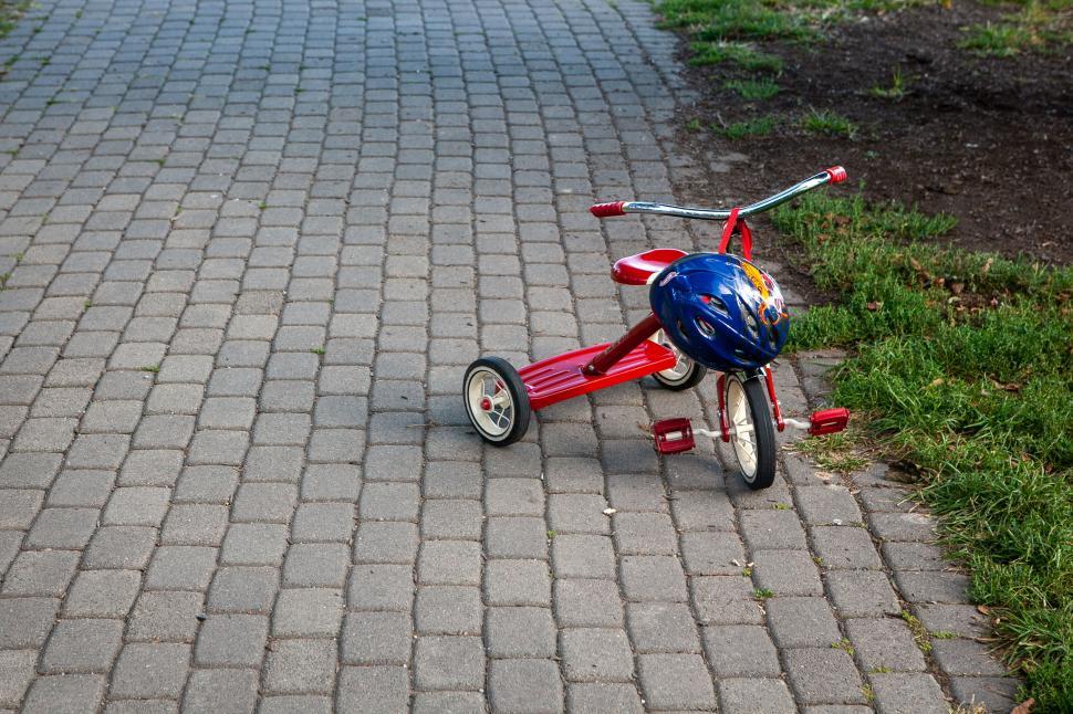 Free Image of Abandoned tricycle and helmet on pavement 