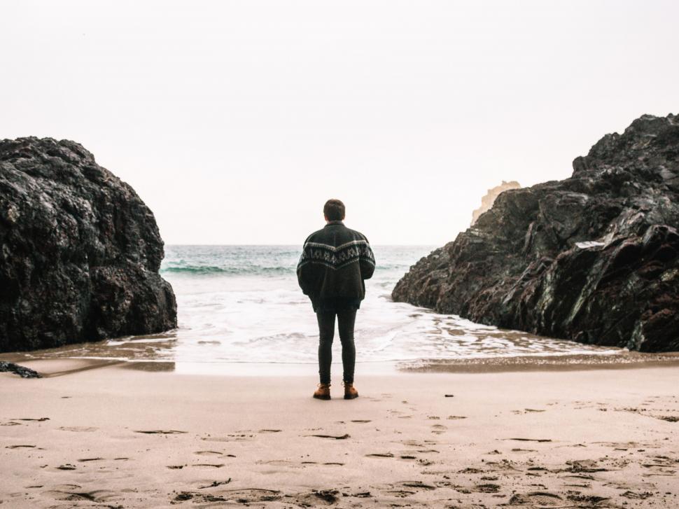 Free Image of Man facing the ocean on the beach 