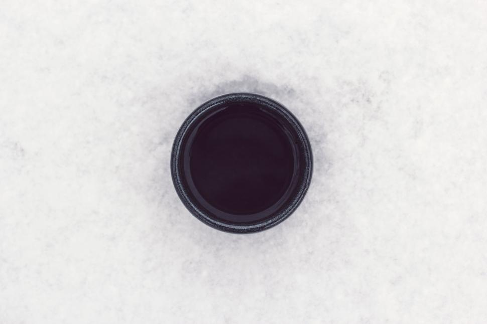 Free Image of Black camera lens cap on white snow 