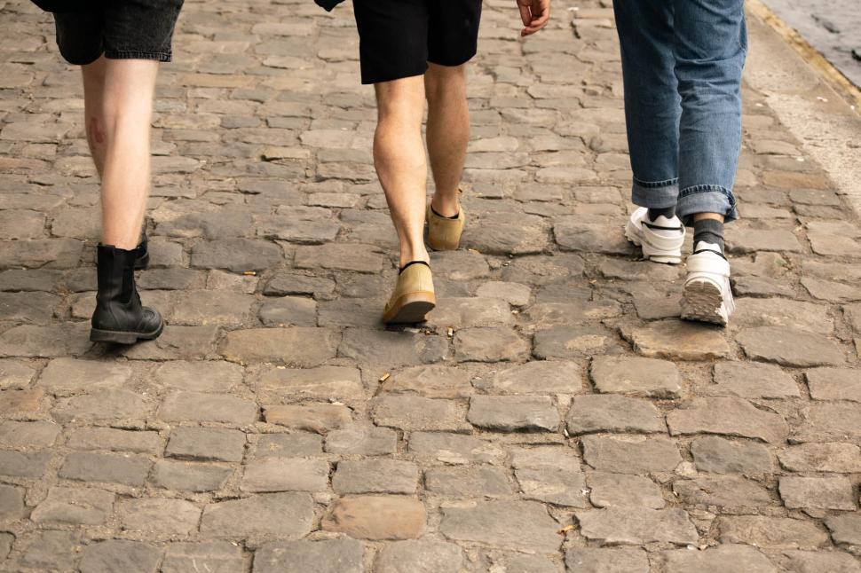 Free Image of Two people walking on cobblestone street 