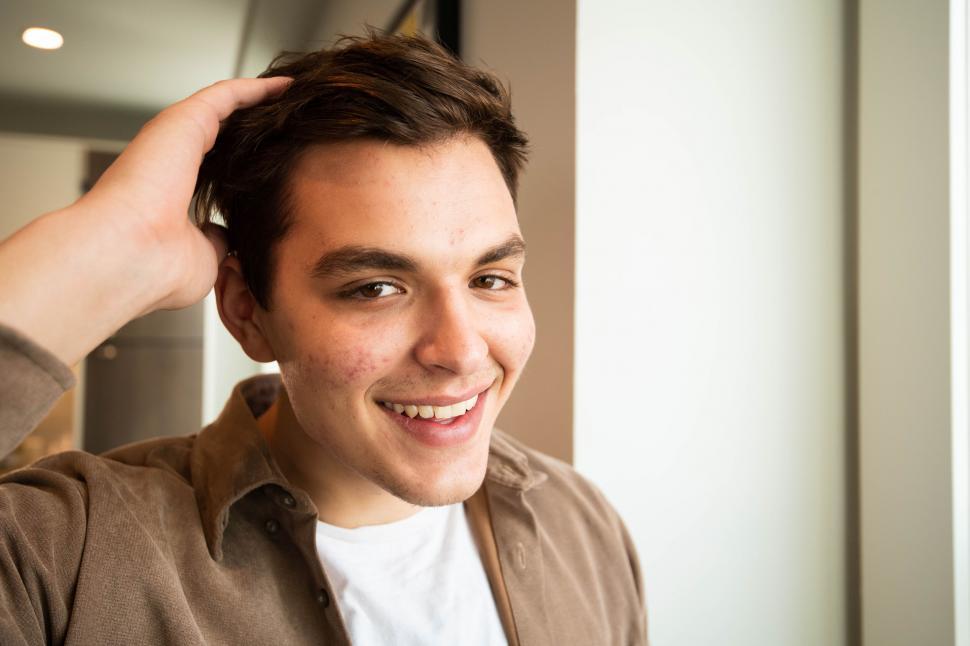 Free Image of Smiling young man scratching his head 