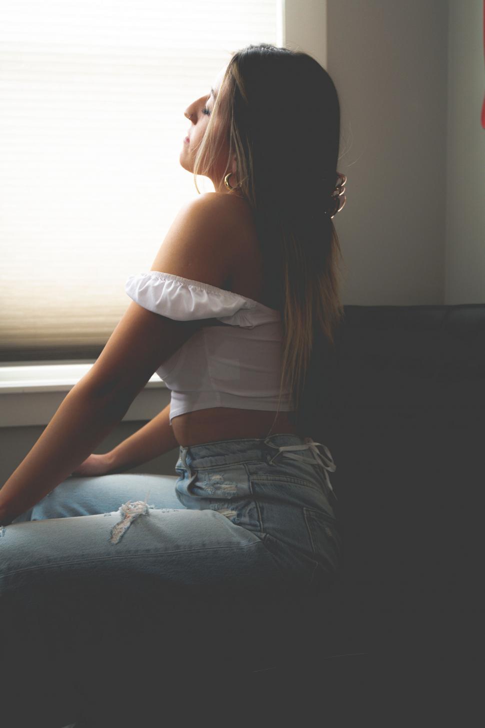 Free Image of Woman sitting by the window in daylight 
