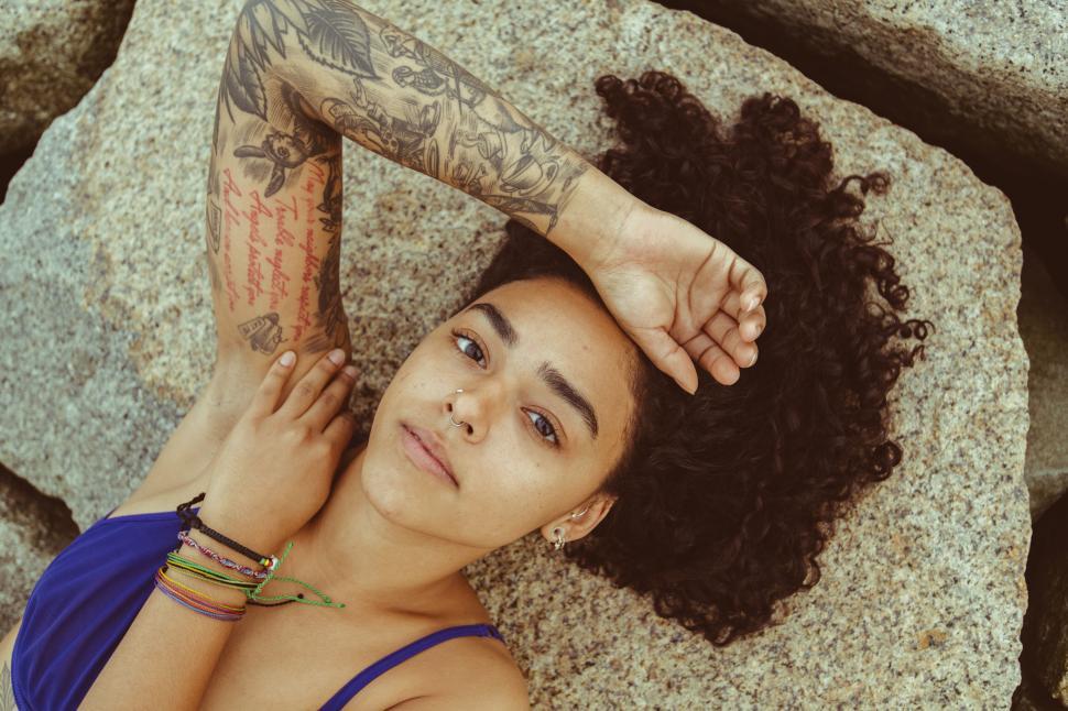 Free Image of Tattooed person relaxing by rocky surface 