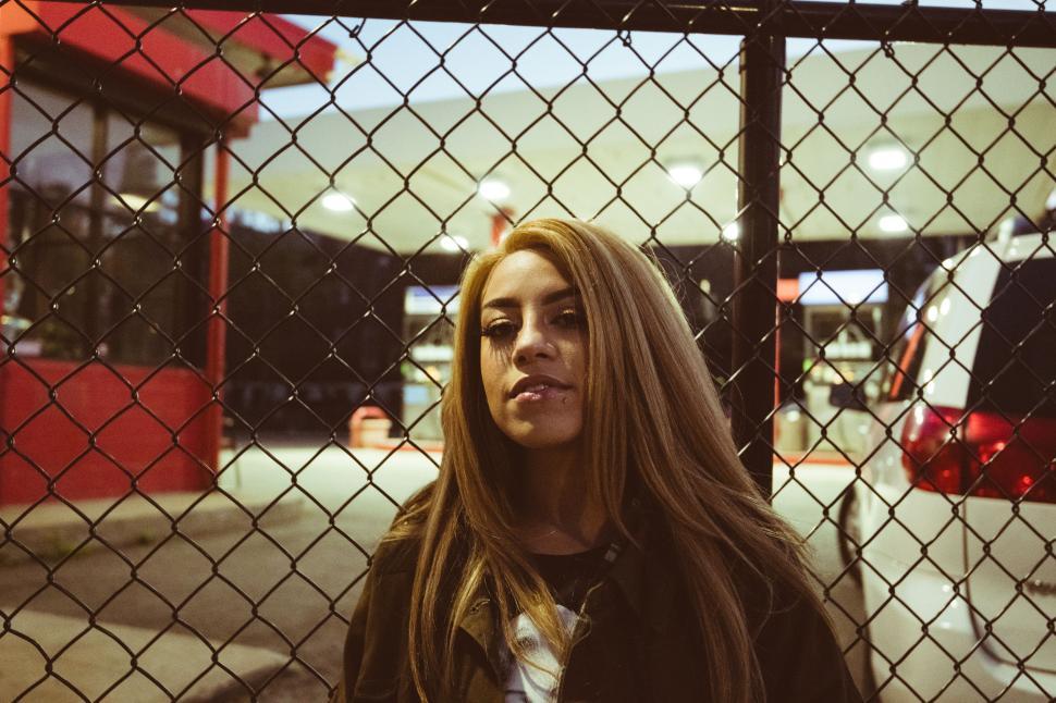 Free Image of Woman standing behind chain link fence 