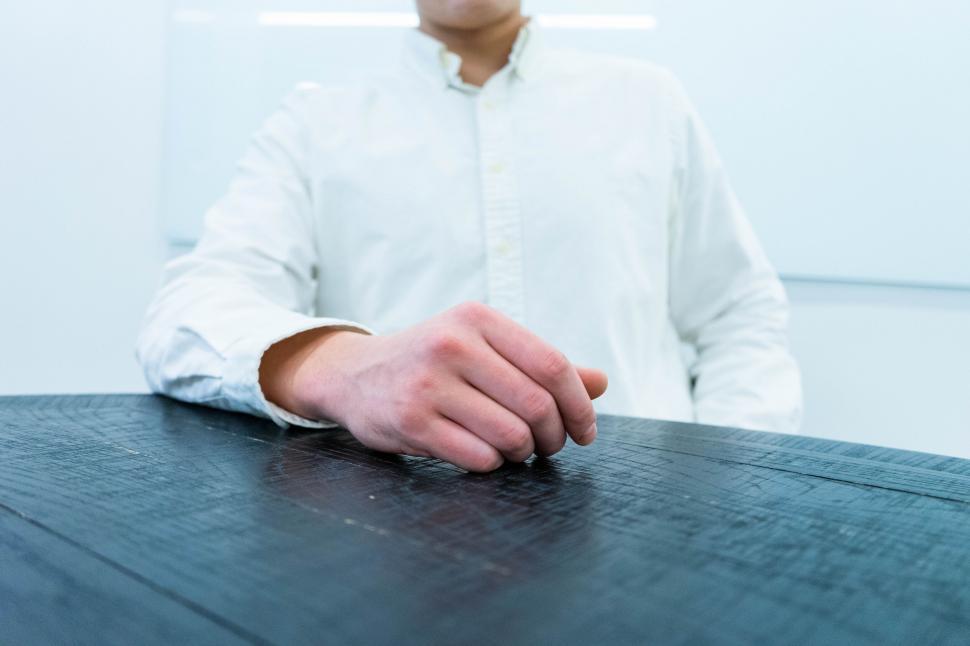 Free Image of Man in white shirt fist on table closeup 