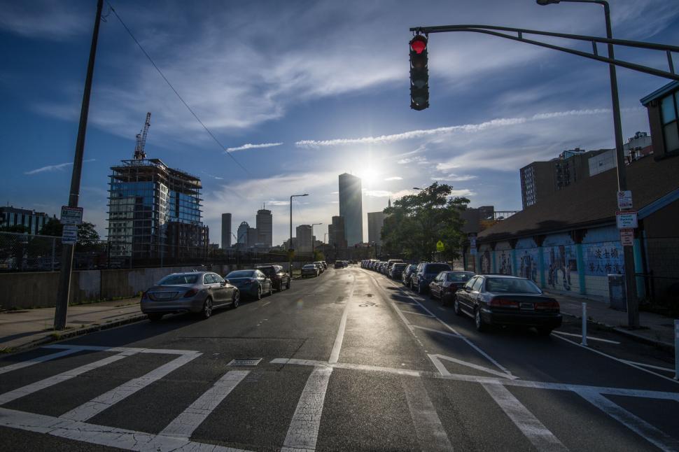 Free Image of Sun setting behind skyscraper-lined road 
