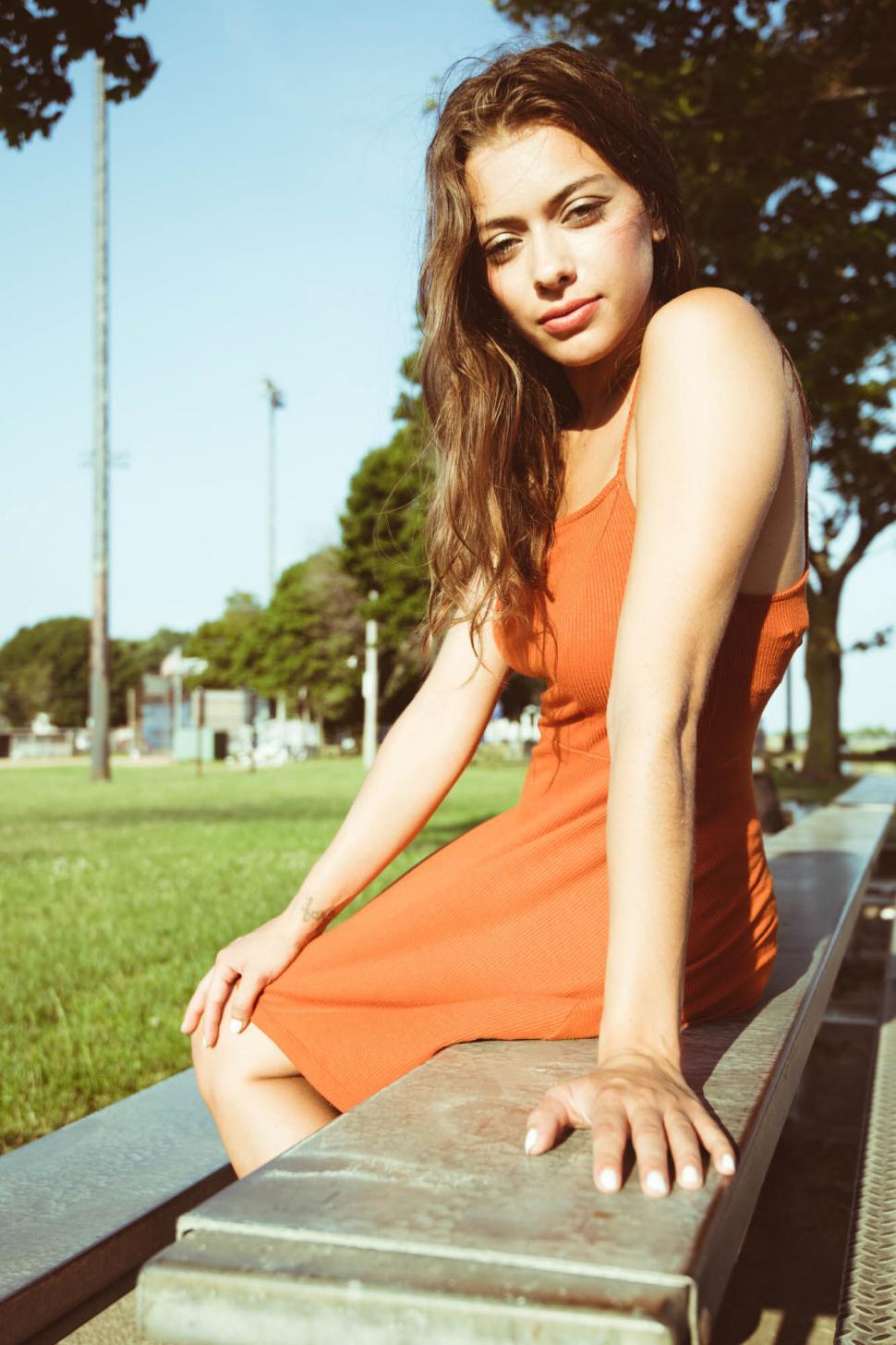 Free Image of Woman in orange dress posing outdoors 