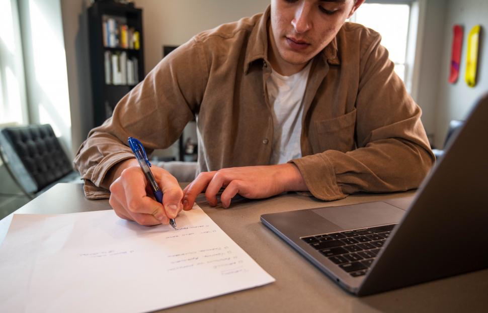 Free Image of Person signing a document at a desk 