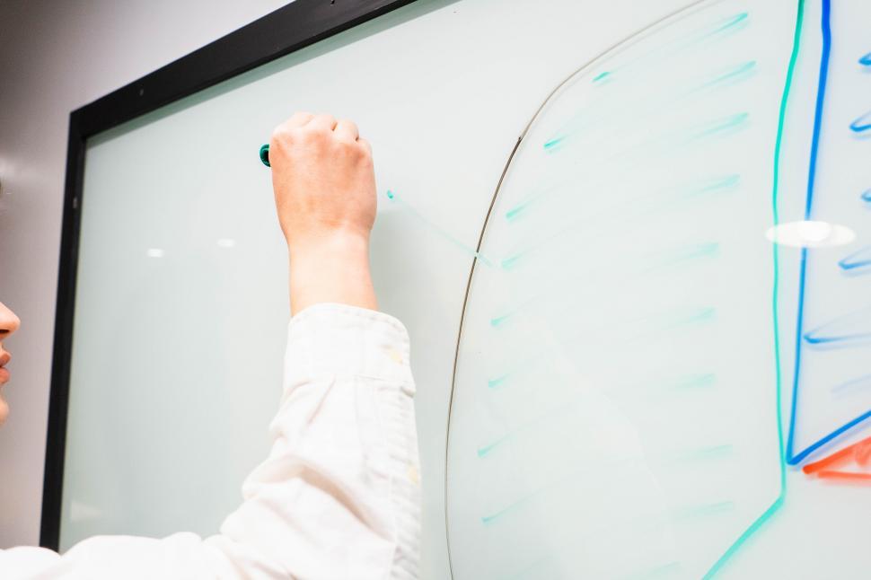Free Image of Person writing on a whiteboard during a meeting 