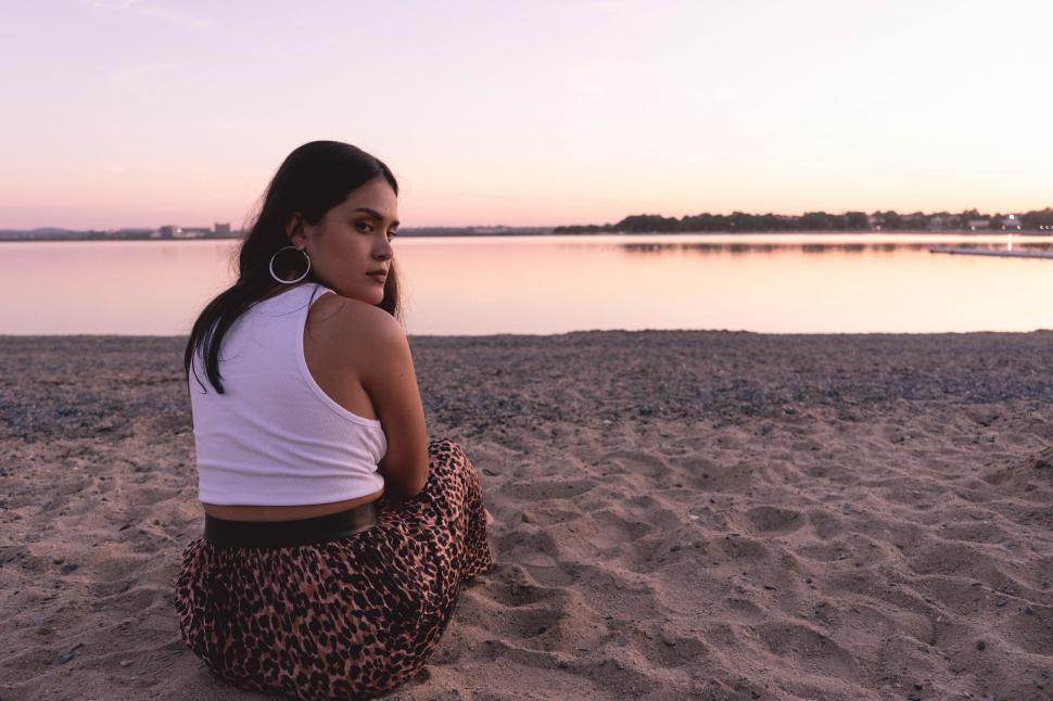 Free Image of Woman sitting on beach during sunset 