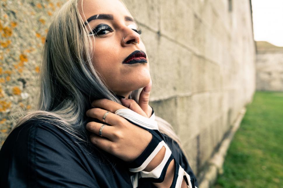 Free Image of Woman embraces herself against concrete wall 
