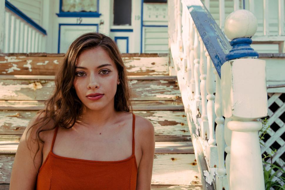Free Image of Woman by a dilapidated porch railing 