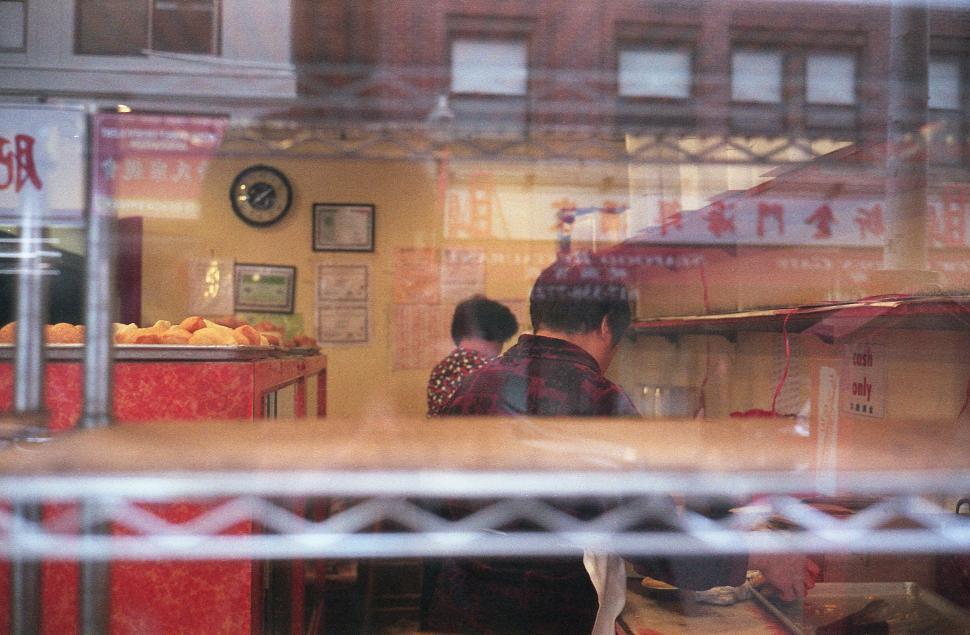 Free Image of Vibrant street market life through chain fence 