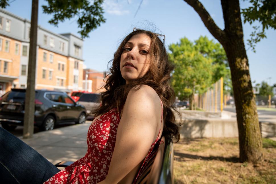Free Image of Young woman sitting on park bench looking back 