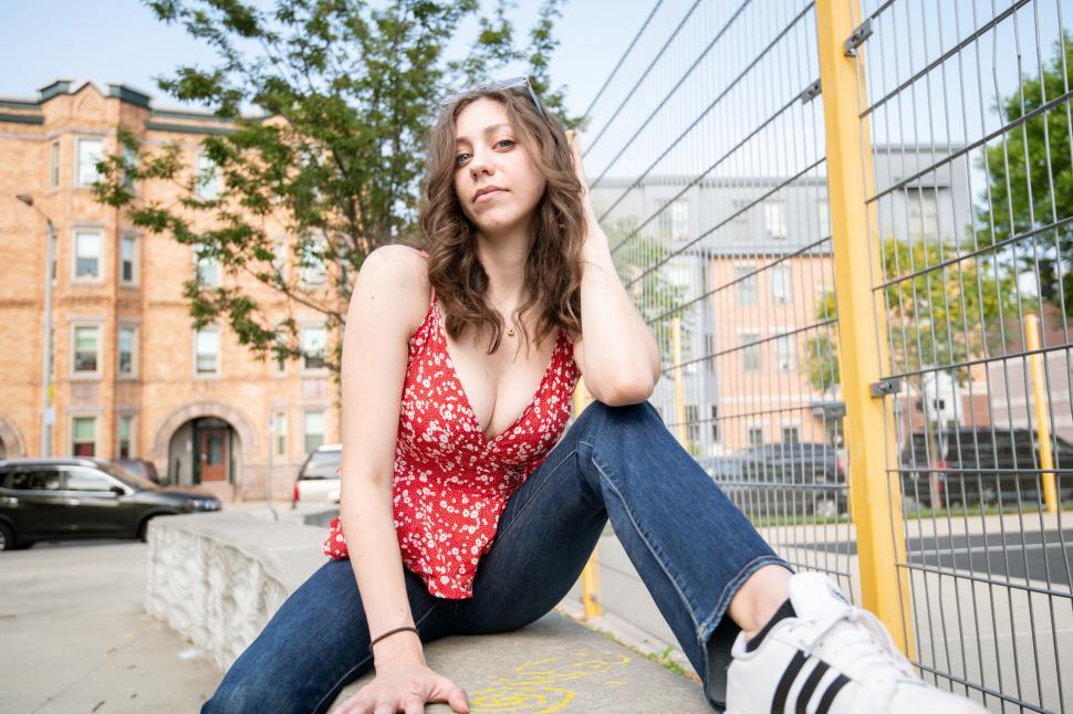 Free Image of Woman in red enjoying a moment on urban sidewalk 