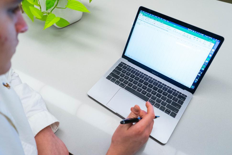 Free Image of Laptop displaying spreadsheet on white table 