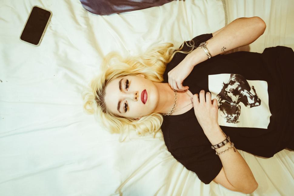 Free Image of Relaxed woman lying with phone and jewelry 