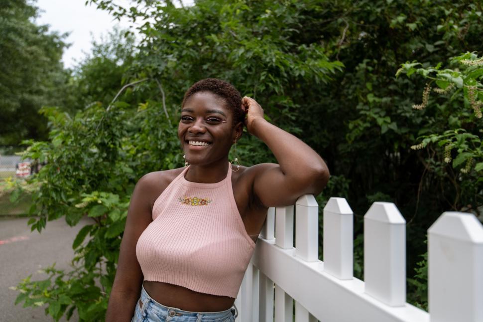 Free Image of Smiling woman by white picket fence 