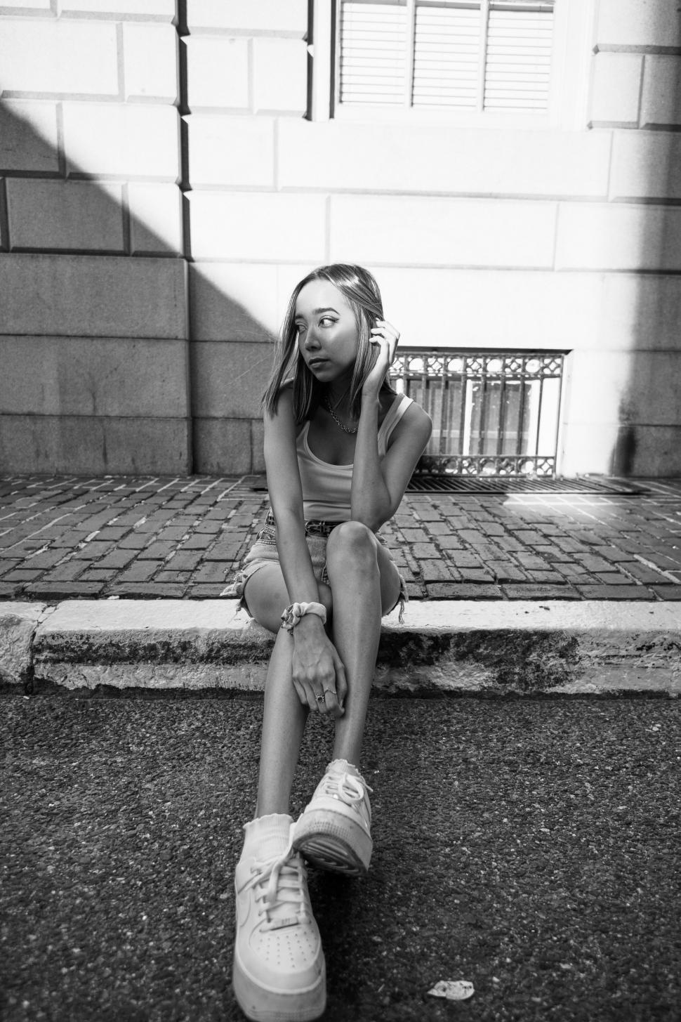 Free Image of Monochrome shot of seated girl in urban setting 