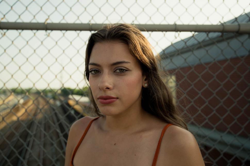 Free Image of Close-up of a woman by a chain-link fence 