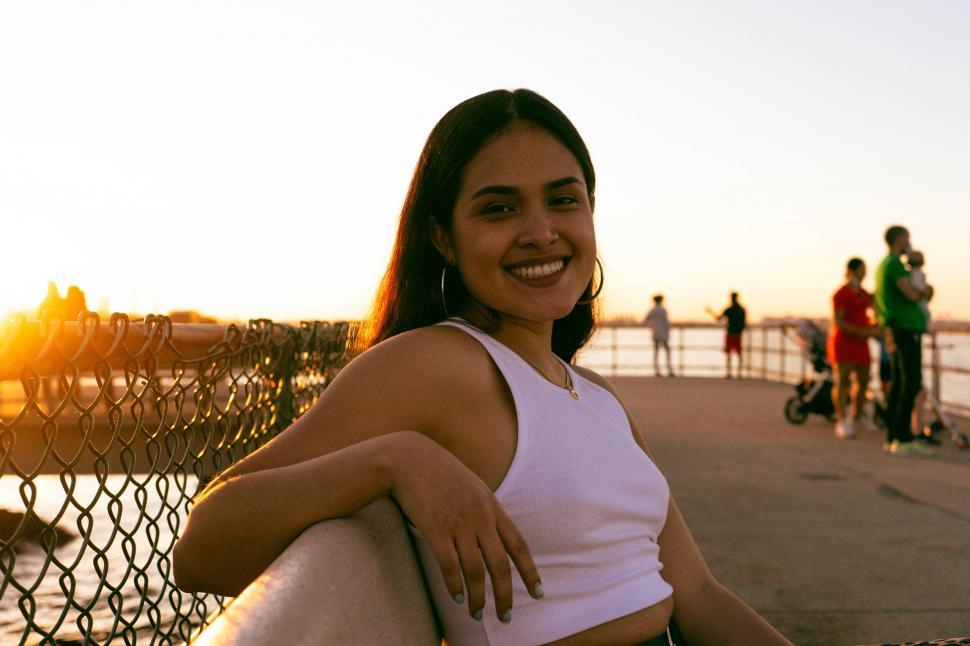 Free Image of Smiling woman enjoying sunset by the water 