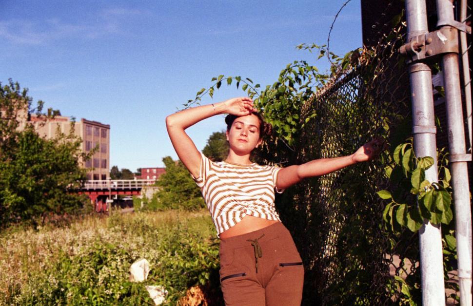 Free Image of Urban style woman leaning against a fence 