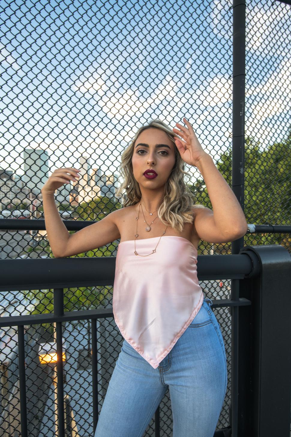 Free Image of Woman adjusting hair with urban backdrop 
