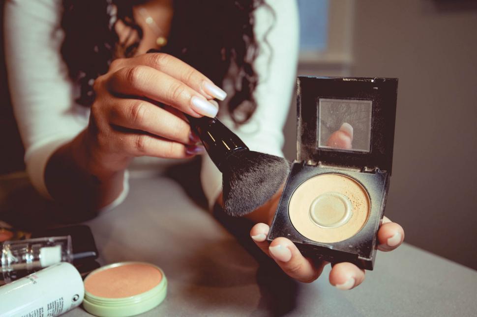 Free Image of Woman applying makeup with a brush 