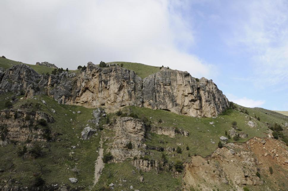 Free Image of Jagged mountainside with clouds and sky in the background 