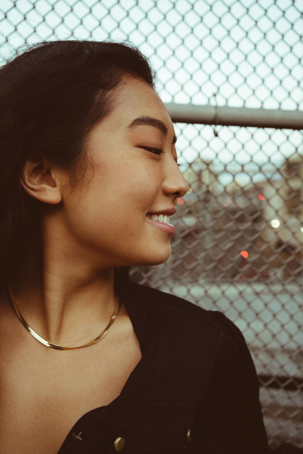 Free Image of Chic woman in front of chain-link fence 