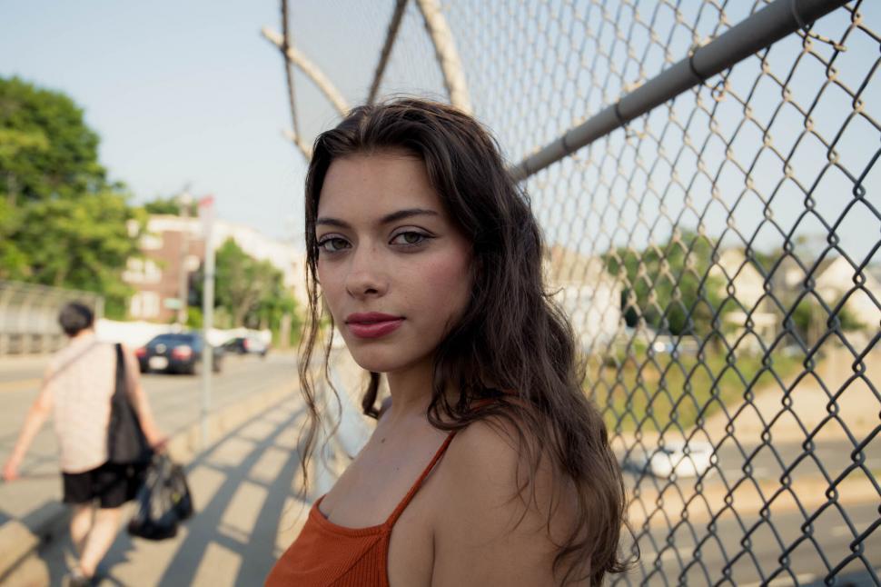 Free Image of Casual Woman by Chain Link Fence 