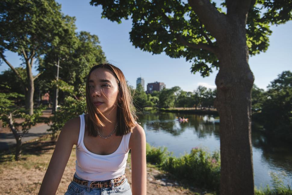 Free Image of Woman by the pond with cityscape background 