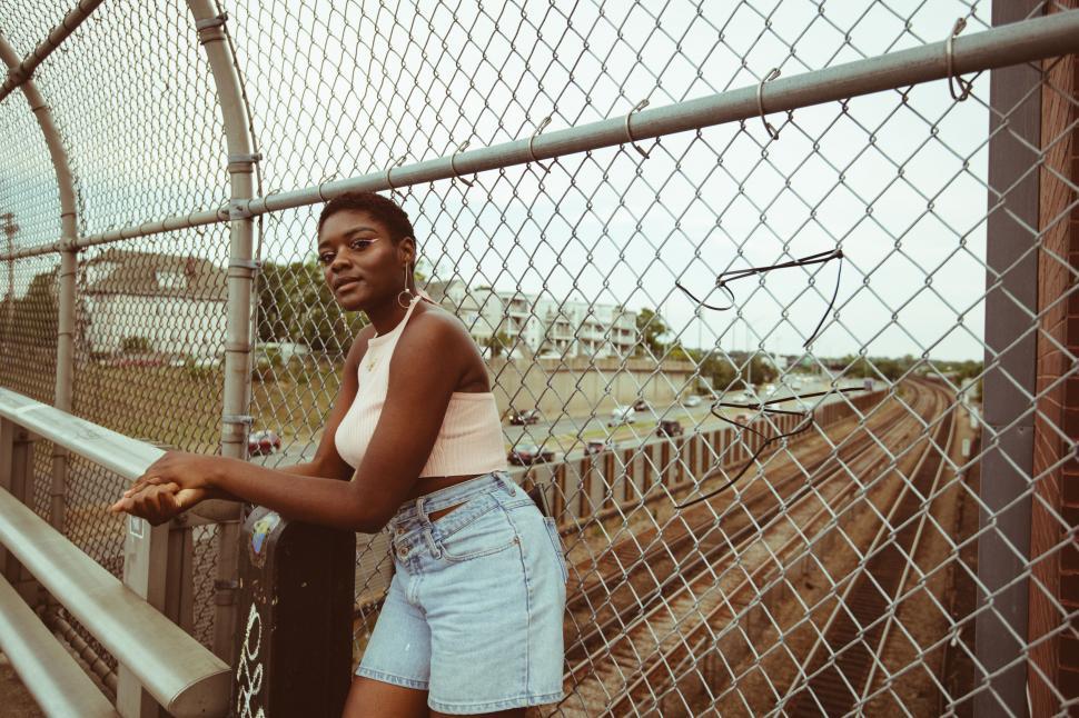 Free Image of Woman leaning on urban fence 