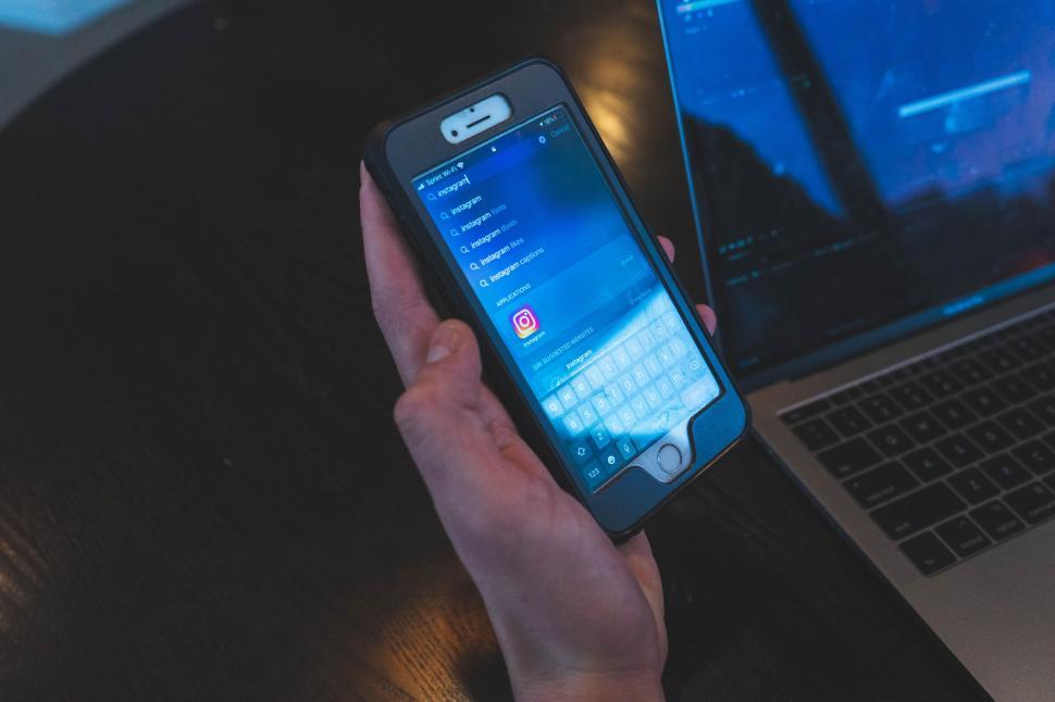 Free Image of Person using iPhone with laptop nearby 
