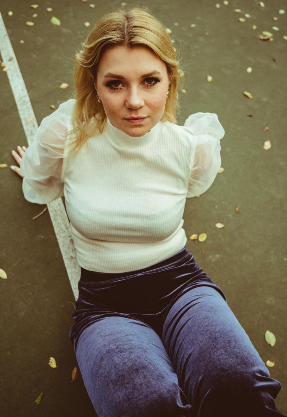 Free Image of Young woman sitting with a modern backdrop 