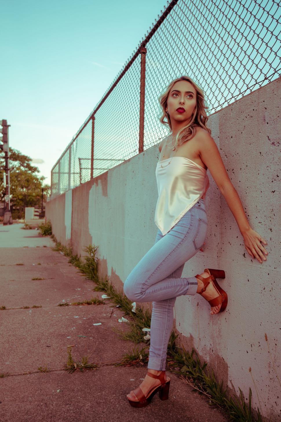 Free Image of Fashion model posing by urban fence 