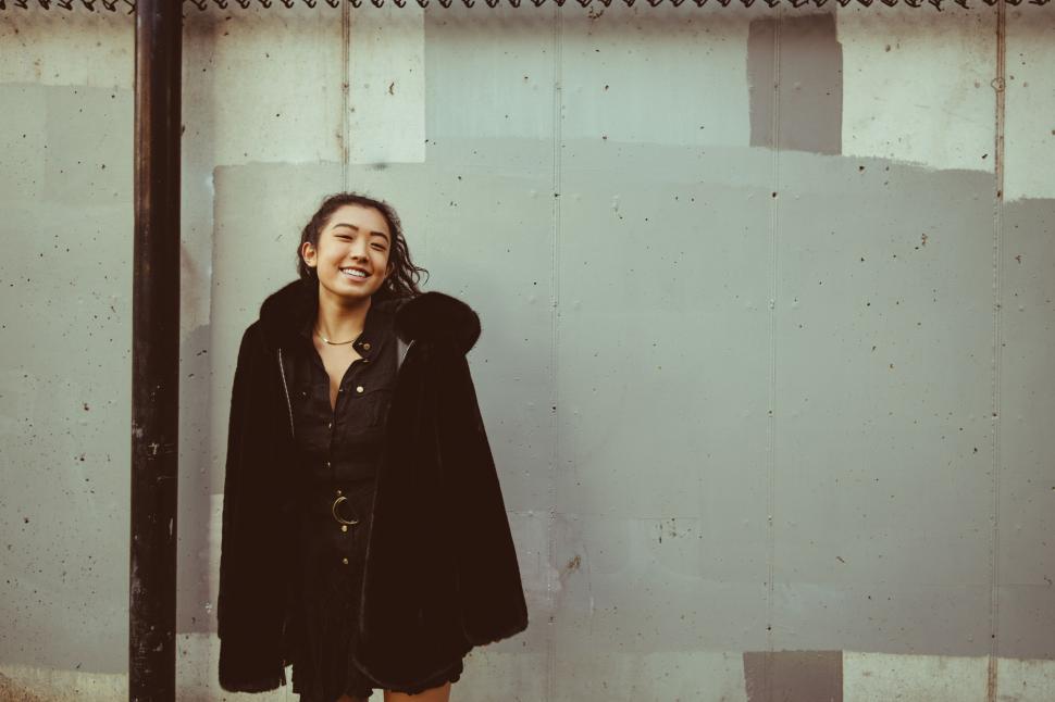 Free Image of Smiling woman against textured urban wall 