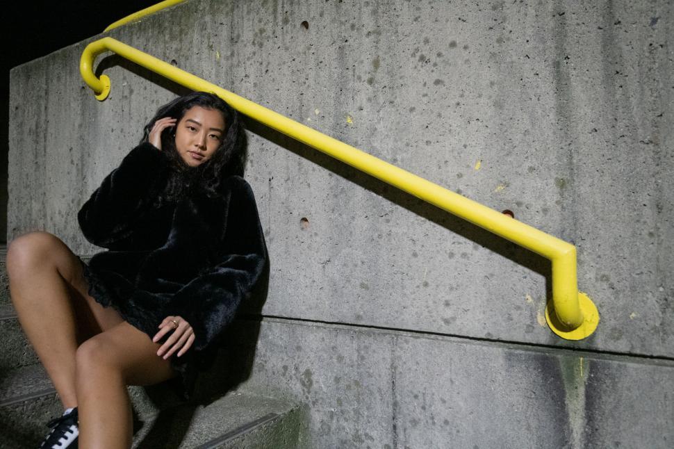 Free Image of Urban woman sitting by yellow railing 