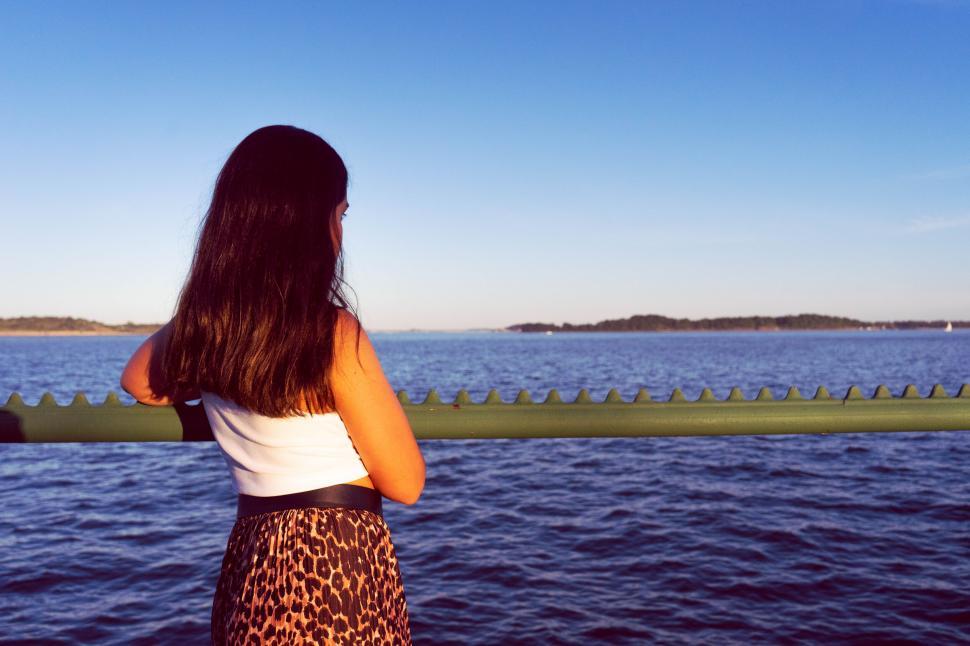 Free Image of Woman looking at water from bridge railing 