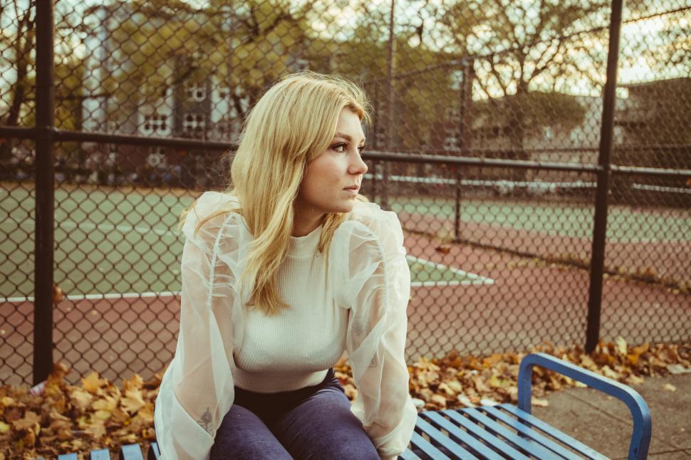 Free Image of Pensive woman sitting on blue bench 